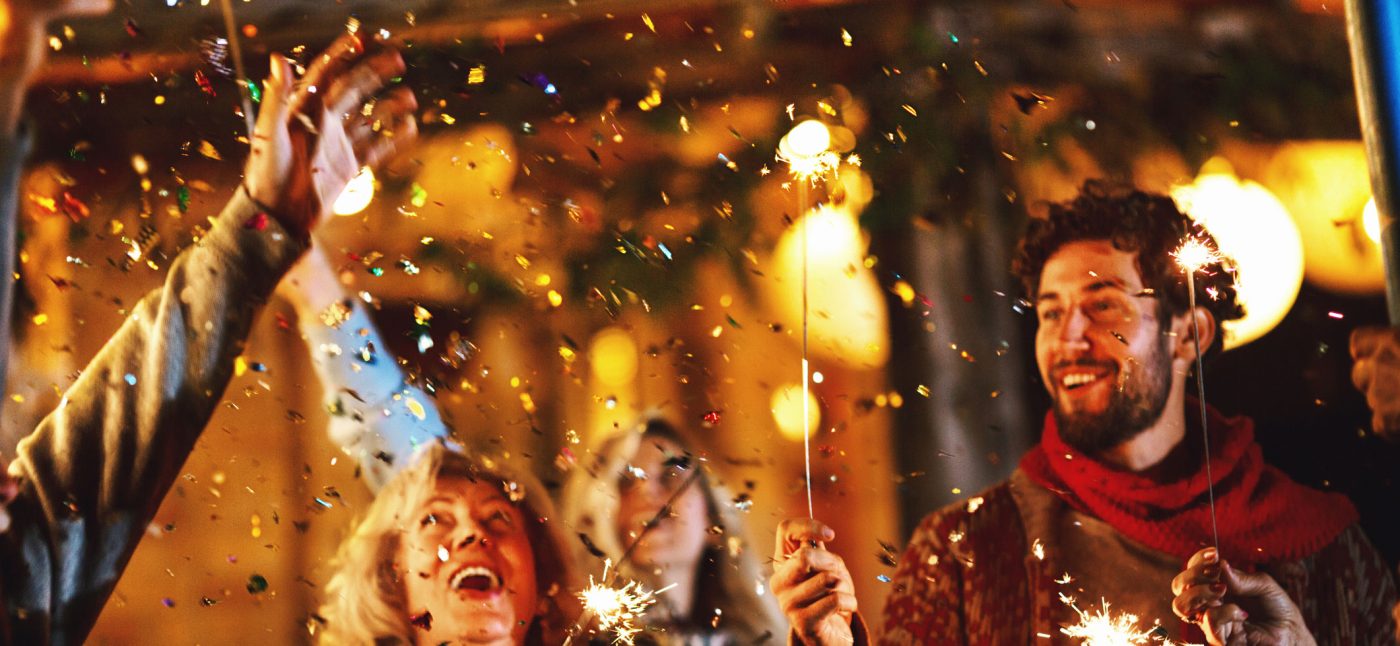 Family dancing and celebrating New Year's Eve outdoors. Confetti in focus.