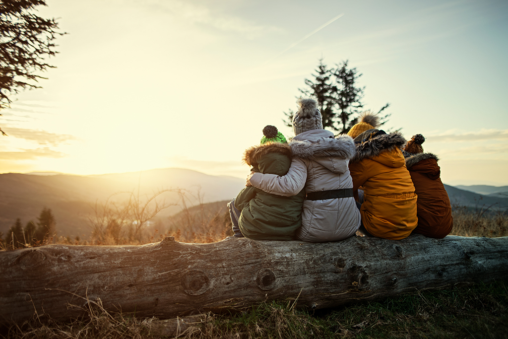 Mother and kids enjoying sunset in mountains.